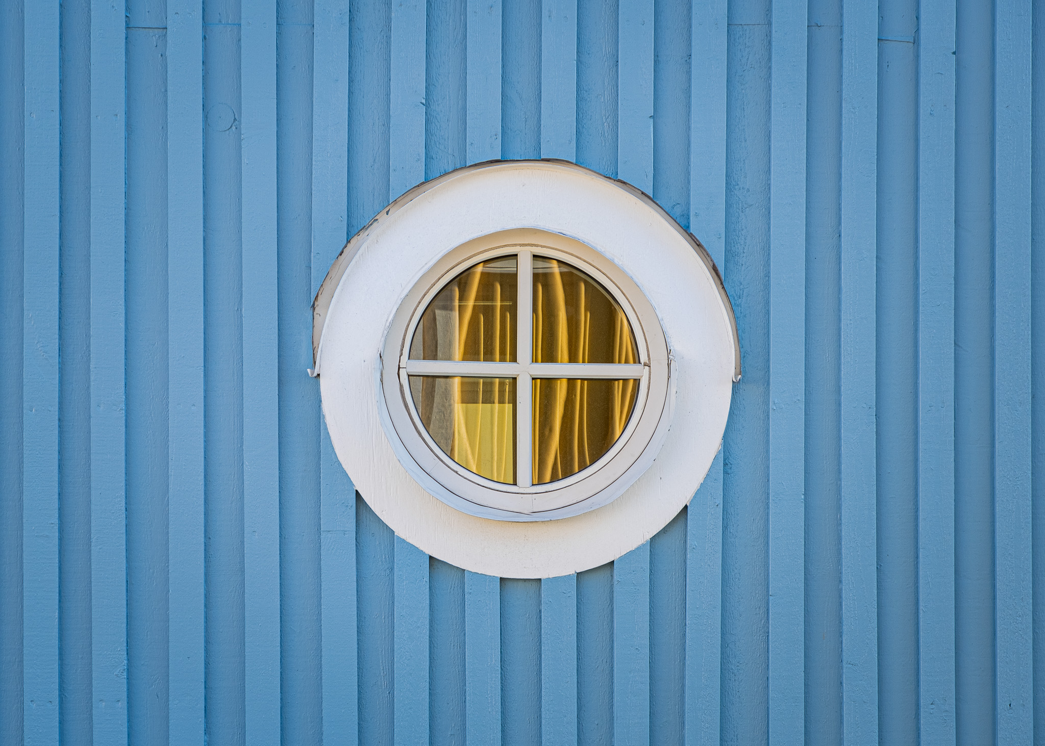 picture of a round window with a blue wooden wall around