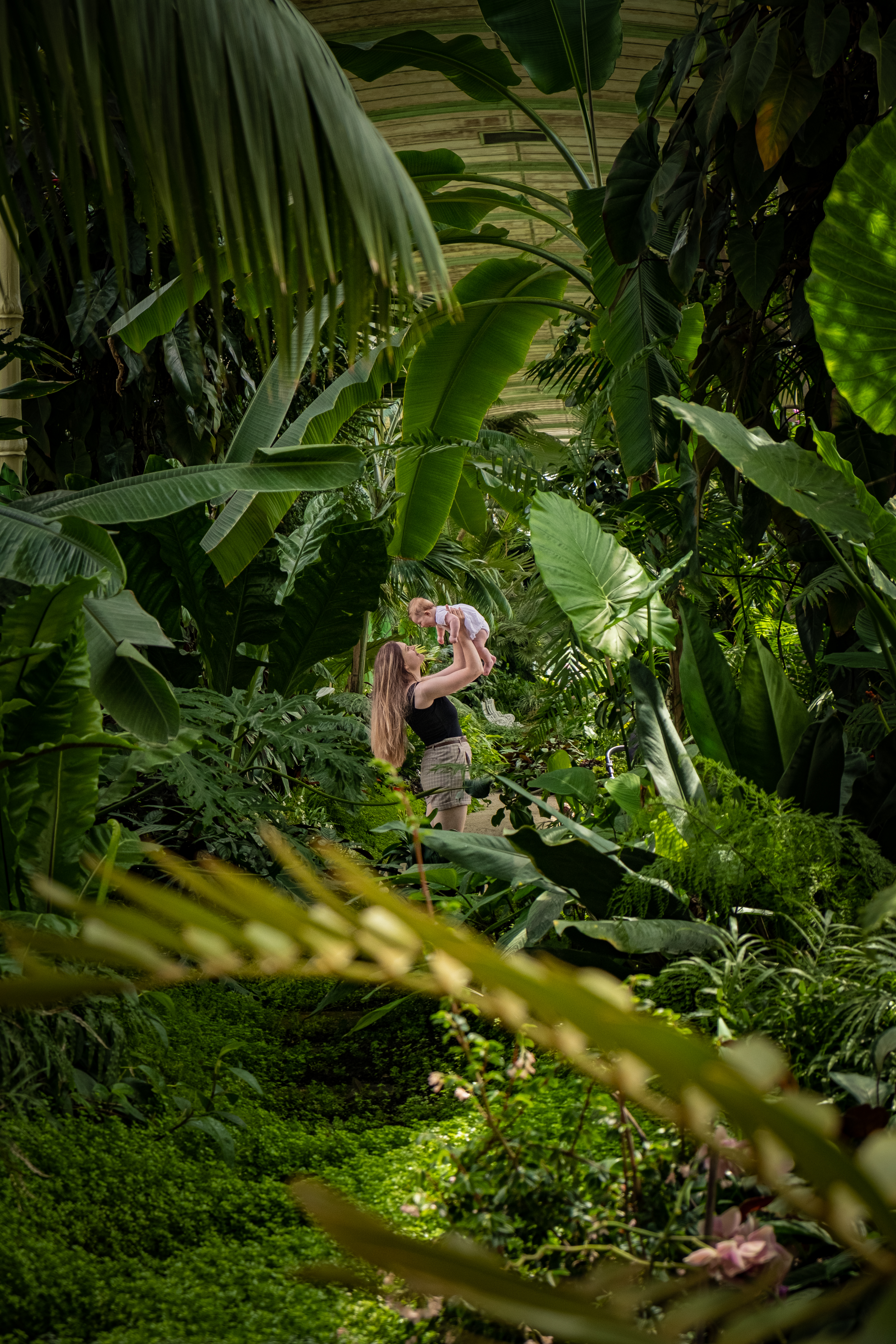 mum with her baby girl in a green tunnel in greenhouse