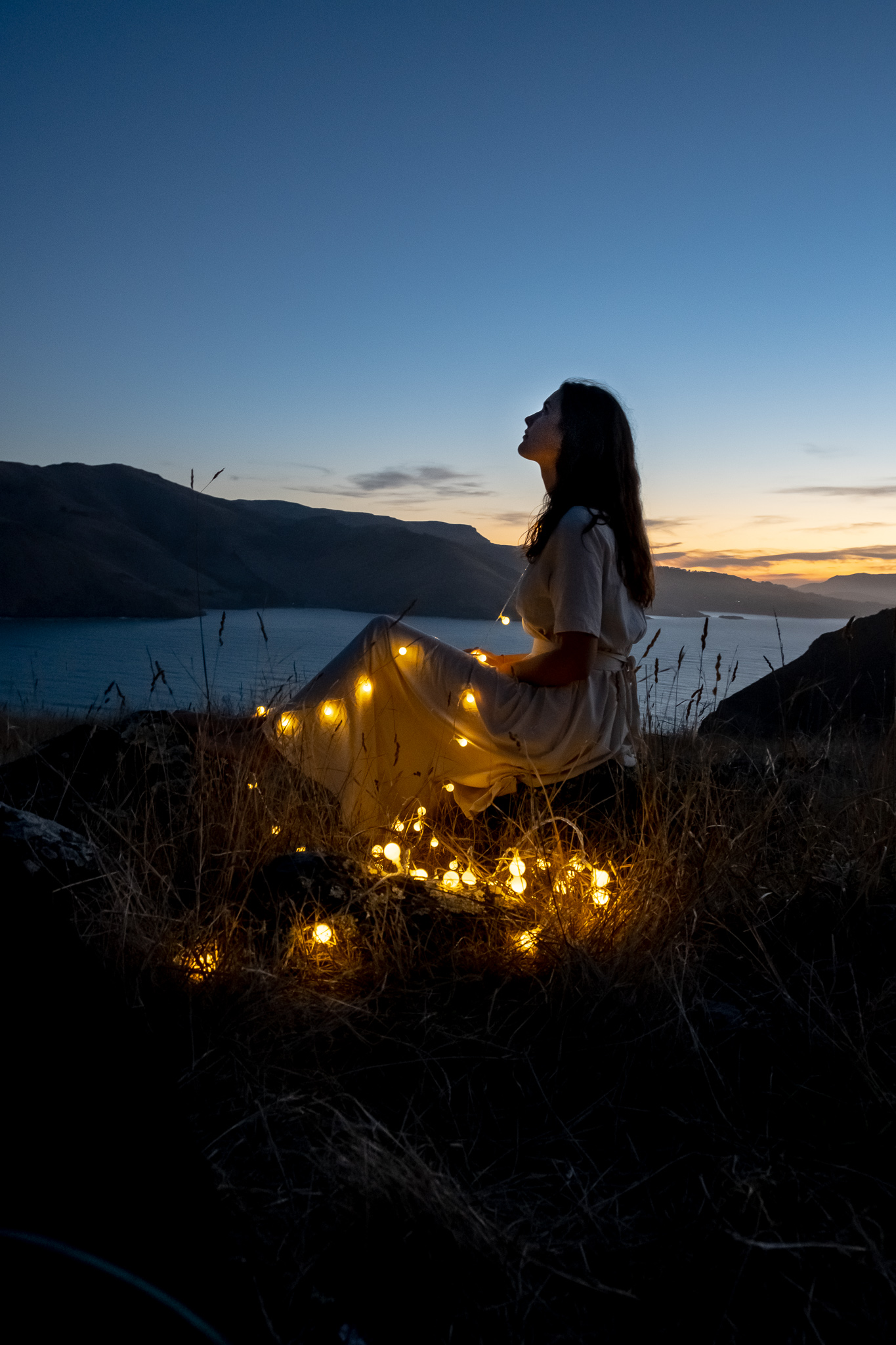 picture of a women with a little lights in dark on a hill